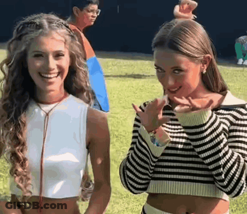 Two Girls Smiling In A Field One In Striped Sweater GIF
