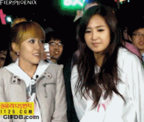 Two Girls Standing Beside Fieryphoenix Sign GIF