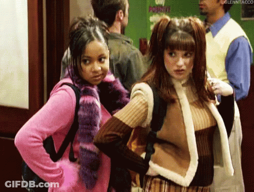 Two Girls Standing In Hallway With Man In Background GIF