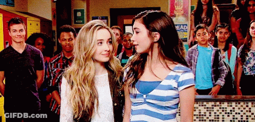 Two Girls Standing Next To Each Other In Front Of A Sign That Says " Head " GIF