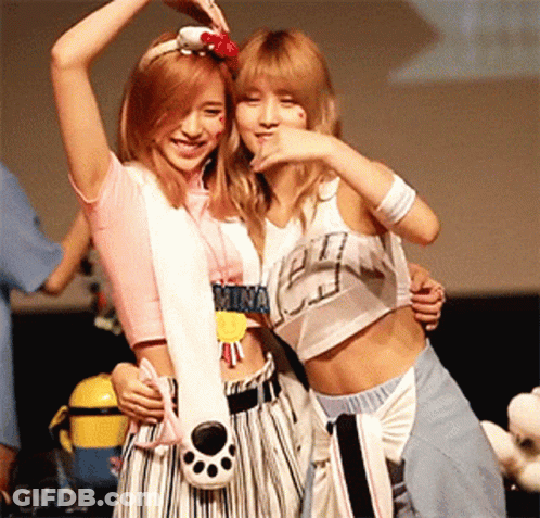 Two Girls Standing Next To Each Other One With Mina Necklace GIF