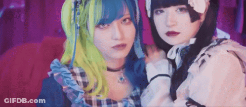 Two Girls With Blue And Green Hair On Red Couch GIF
