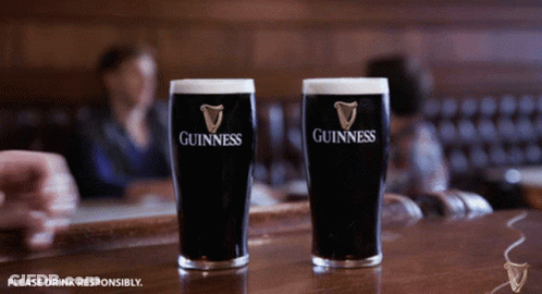 Two Glasses Of Guinness Sit On A Bar In A Restaurant GIF