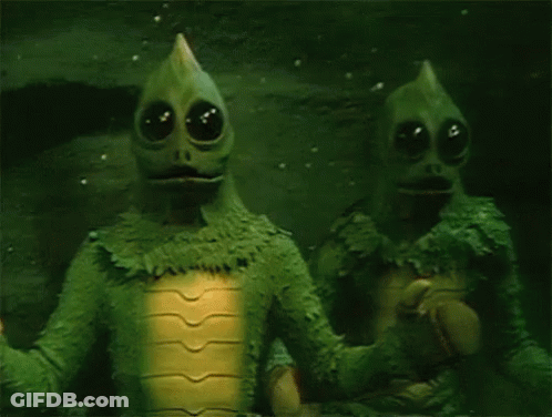 Two Green Aliens Standing Together GIF