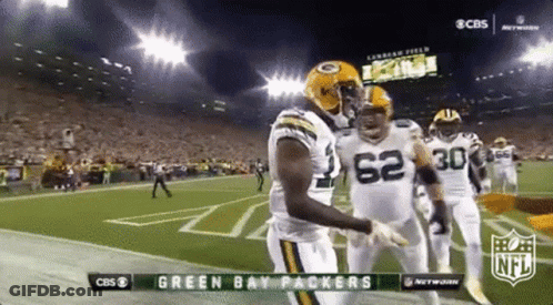 Two Green Bay Packers Players Are Hugging Each Other On The Field During A Football Game . GIF
