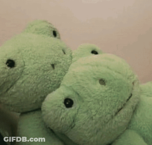 Two Green Teddy Bears Are Hugging Each Other Against A Pink Wall GIF