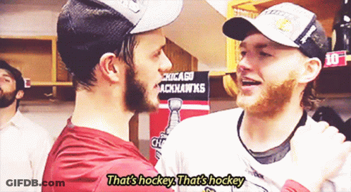 Two Hockey Players Are Hugging In Front Of A Chicago Blackhawks Sign GIF