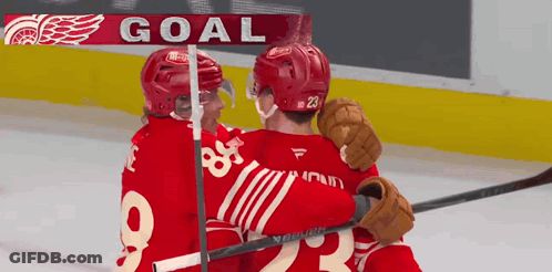 Two Hockey Players Are Hugging In Front Of A Sign That Says Goal GIF