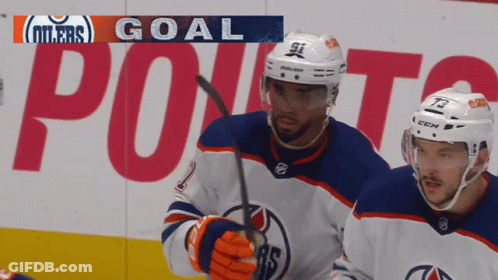Two Hockey Players Are Standing In Front Of A Banner That Says Oilers Goal GIF