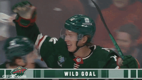 Two Hockey Players Celebrate A Wild Goal With A Banner Behind Them GIF