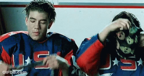 Two Hockey Players In Locker Room One Wearing Mask GIF