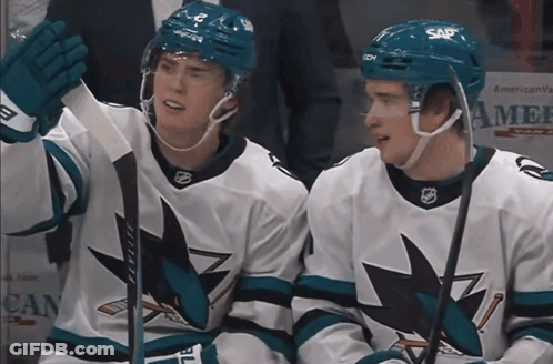 Two Hockey Players In Sap Helmets Sitting On Ice GIF