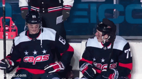 Two Hockey Players Sitting On Ice In Caps Jerseys GIF