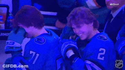 Two Hockey Players Wearing Blue Jerseys With The Number 71 And 2 On Them GIF