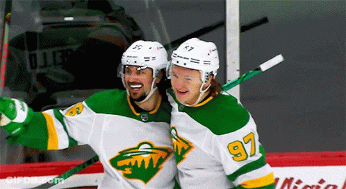 Two Hockey Players Wearing Green And White Uniforms With The Number 97 GIF