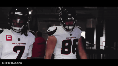 Two Houston Football Players Are Standing Next To Each Other In A Dark Room GIF