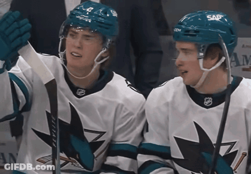Two Ice Hockey Players Wearing Sap Helmets Are Sitting Next To Each Other GIF