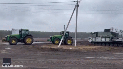 Two John Deere Tractors Parked Next To Each Other GIF