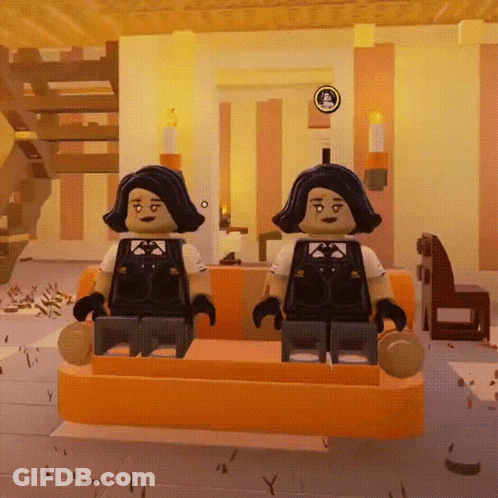 Two Lego Figures Are Sitting On A Orange Couch In A Room GIF