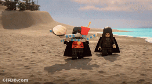 Two Lego Figures Standing On A Sandy Beach With One Holding A Hamburger And The Other Holding A French Fries Bucket GIF