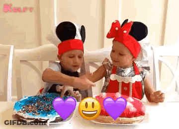 Two Little Girls Are Sitting At A Table With Plates Of Food . One Of The Girls Is Wearing A Mickey Mouse Hat . GIF