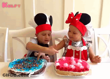 Two Little Girls Are Sitting At A Table With Two Cakes GIF