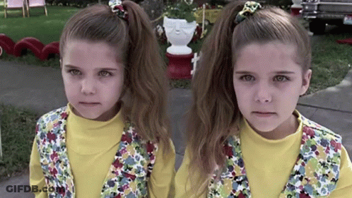 Two Little Girls Are Standing Next To Each Other On The Sidewalk GIF