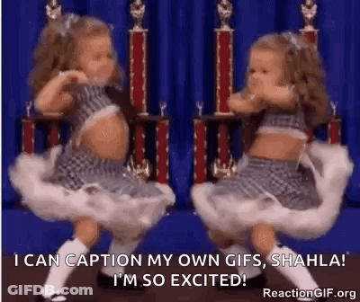 Two Little Girls Dancing In Front Of Trophies And Blue Curtain GIF