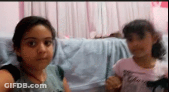 Two Little Girls Making Funny Faces On Couch GIF