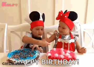 Two Little Girls Wearing Mickey Mouse Hats Are Sitting At A Table With Birthday Cakes . GIF