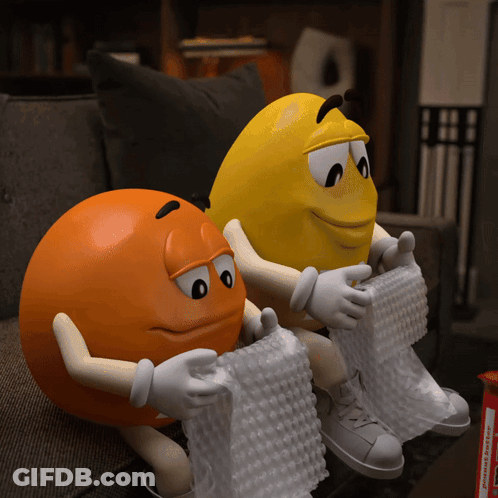Two M&Ms Sitting On Couch With Bubble Wrap GIF
