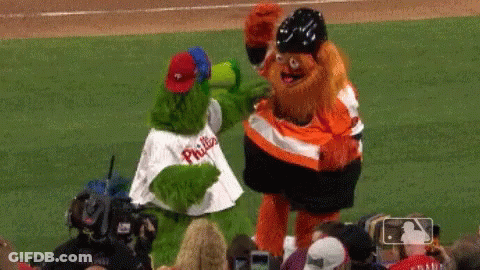 Two Mascots From The Phillies Are Standing On A Baseball Field GIF