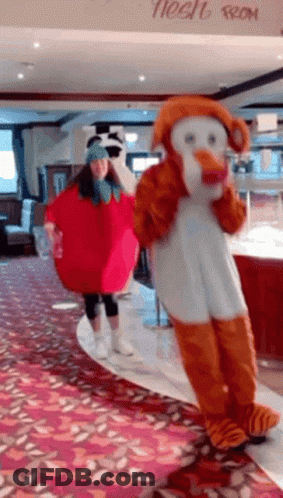 Two Mascots In Front Of Tinsel Sign GIF