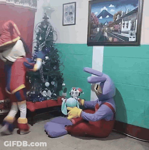 Two Mascots With Stuffed Animal Near Christmas Tree GIF