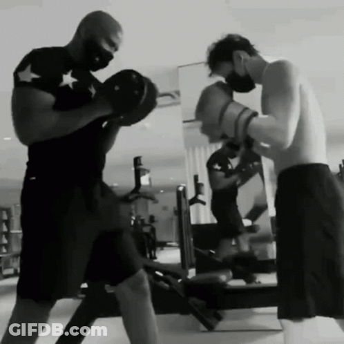 Two Men Are Boxing In A Gym Wearing Masks . GIF