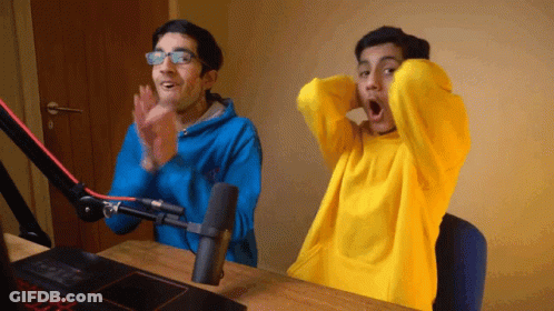 Two Men Are Clapping In Front Of A Microphone And One Of Them Is Wearing A Yellow Sweater GIF