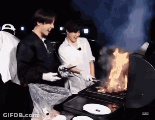 Two Men Are Cooking Food On A Grill While Another Man Watches . GIF