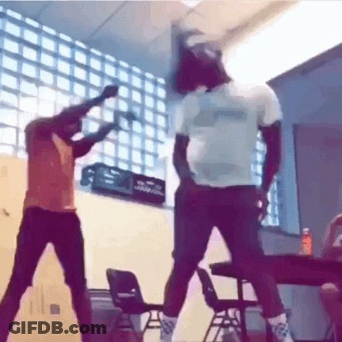 Two Men Are Dancing In A Classroom With Chairs And A Crate In The Background . GIF