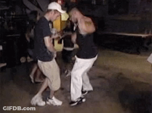 Two Men Are Dancing In A Dark Room While A Man Holds A Guitar . GIF