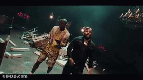 Two Men Are Dancing In A Dark Room With A Chandelier Hanging From The Ceiling . GIF