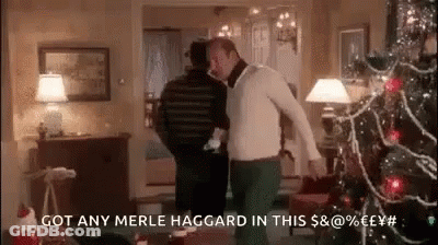 Two Men Are Dancing In A Living Room With A Christmas Tree . GIF