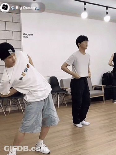 Two Men Are Dancing In A Room With A Big Ocean Logo GIF