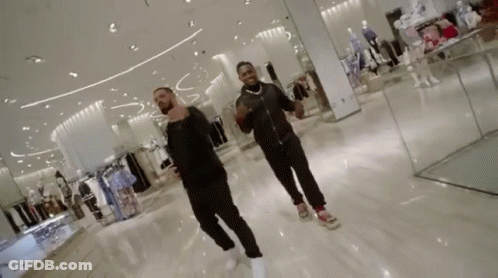 Two Men Are Dancing In A Shopping Mall While Looking At Clothes . GIF
