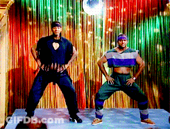 Two Men Are Dancing In Front Of A Colorful Curtain GIF