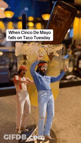 Two Men Are Dancing In Front Of A Giant Margarita Glass With A Bottle Of Tequila In The Background GIF