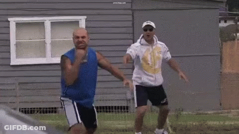 Two Men Are Dancing In Front Of A Gray House . GIF