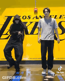 Two Men Are Dancing In Front Of A Los Angeles Lakers Poster GIF