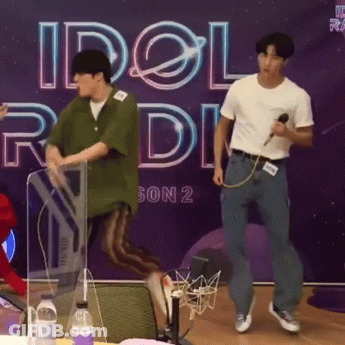 Two Men Are Dancing In Front Of A Sign That Says Idol Radio Season 2 GIF