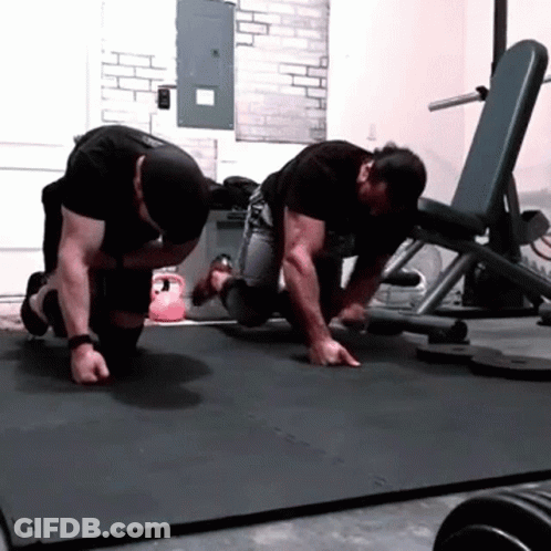 Two Men Are Doing Push Ups On A Mat With The Letter S On It GIF
