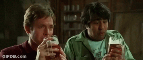 Two Men Are Drinking Beer Together In A Bar And Talking To Each Other . GIF